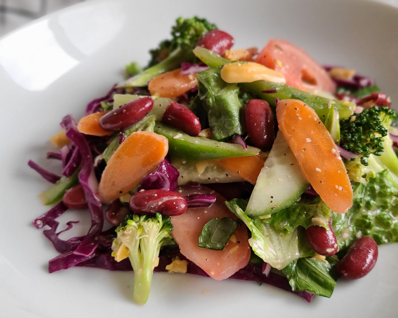 salad with beans, carrots, lettuce, cucumbers, and broccoli on a plate